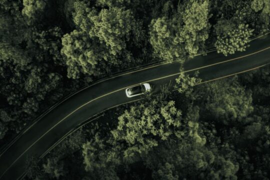 View above a forest shared by a road with an xpeng vehicle